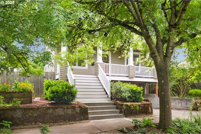 obstructed view of property featuring stairs, a porch, and fence