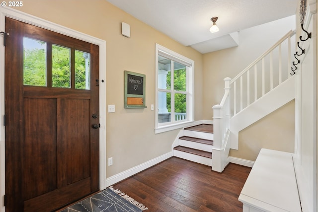 entrance foyer featuring stairs, baseboards, and dark wood-style floors