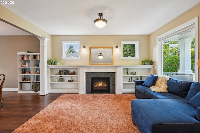 living area with healthy amount of natural light, wood finished floors, a fireplace, decorative columns, and a textured ceiling