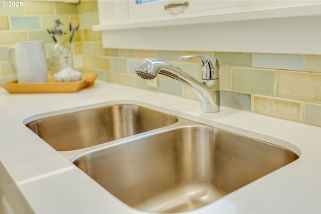 interior details featuring a sink, decorative backsplash, and light countertops