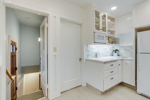 kitchen featuring decorative backsplash, white appliances, glass insert cabinets, and white cabinets