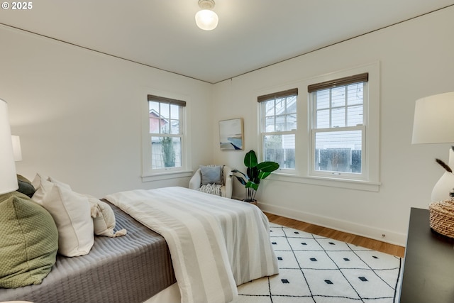 bedroom featuring light wood finished floors, multiple windows, and baseboards