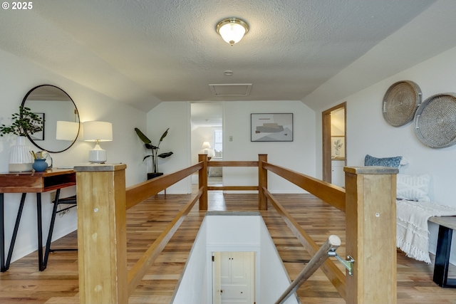 stairs with lofted ceiling, wood finished floors, and a textured ceiling