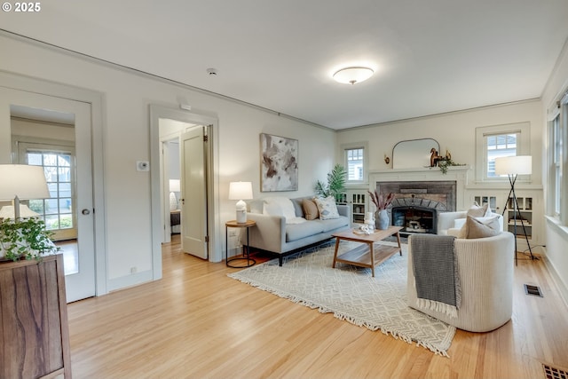 living room featuring visible vents, a healthy amount of sunlight, a fireplace, and wood finished floors