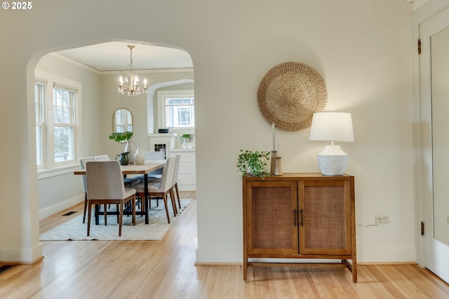 dining room featuring light wood-style floors, arched walkways, and baseboards