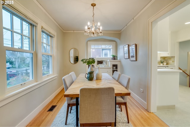 dining area with light wood-type flooring, visible vents, and ornamental molding