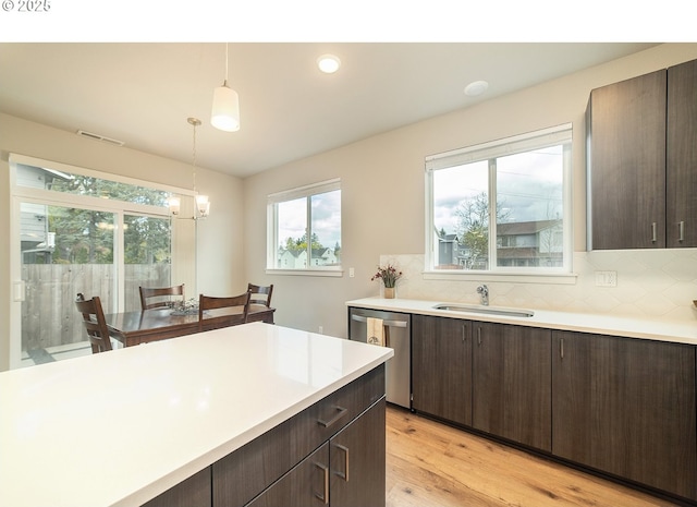 kitchen featuring dishwasher, sink, dark brown cabinetry, and decorative light fixtures