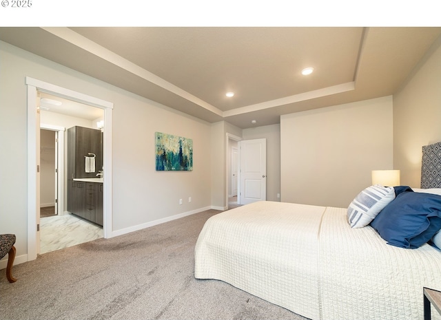 carpeted bedroom with a tray ceiling and ensuite bath