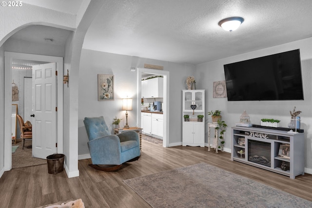 3911 E 16th Ave, Eugene, OR 97403 - living room featuring arched walkways, wood finished floors, and a textured ceiling