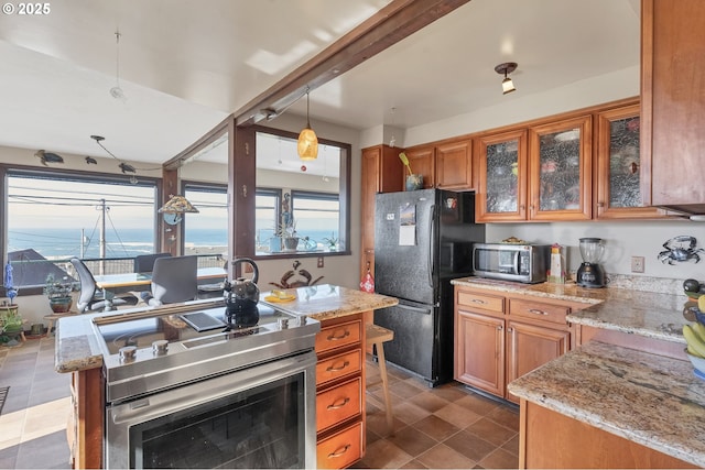 kitchen with brown cabinetry, light stone countertops, and stainless steel appliances
