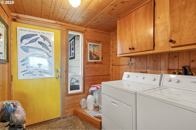washroom featuring wooden ceiling, wood walls, cabinet space, and washing machine and dryer