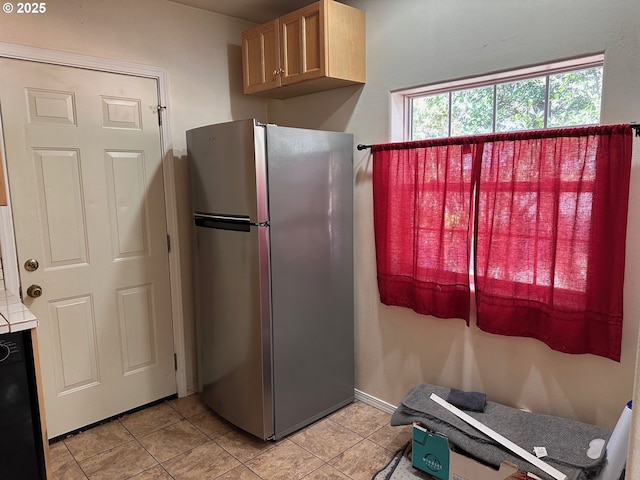 kitchen with stainless steel fridge, light tile patterned floors, and light brown cabinets