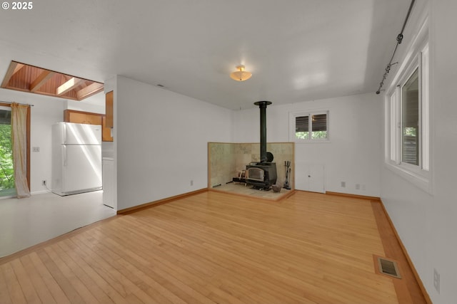 78650 Rat Creek Rd, Cottage Grove, OR 97424 - unfurnished living room with a wood stove, light wood finished floors, healthy amount of natural light, and baseboards