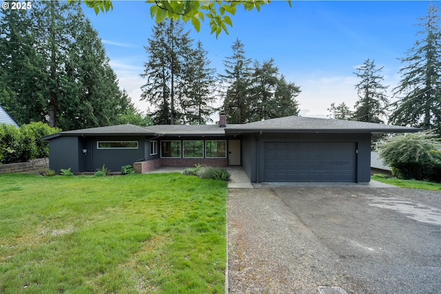 view of front facade featuring concrete driveway, a front yard, a chimney, and an attached garage