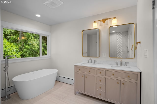 full bathroom featuring double vanity, a freestanding bath, baseboard heating, and a sink