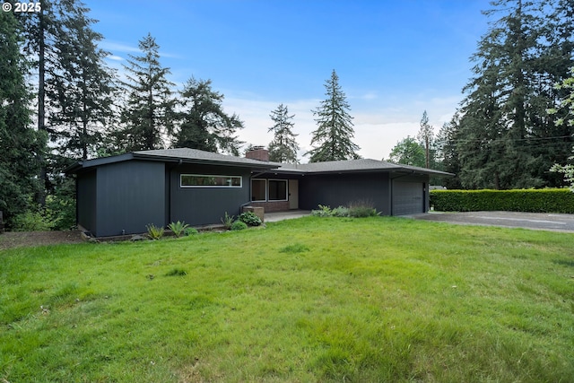 prairie-style house with a chimney, a front lawn, aphalt driveway, and a garage