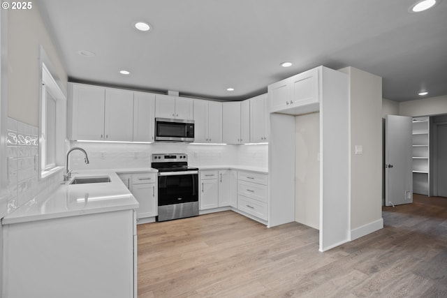 kitchen featuring a sink, white cabinets, light countertops, tasteful backsplash, and appliances with stainless steel finishes