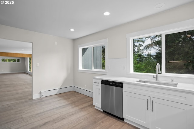 kitchen featuring a sink, white cabinetry, light countertops, stainless steel dishwasher, and light wood-style floors