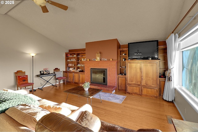 living room featuring a ceiling fan, visible vents, a brick fireplace, lofted ceiling, and light wood-style floors