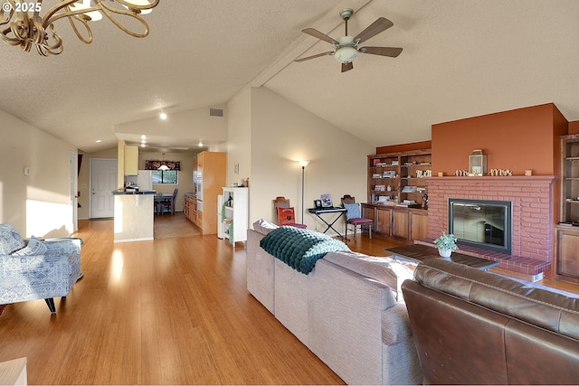 living area with a textured ceiling, light wood finished floors, ceiling fan with notable chandelier, and lofted ceiling