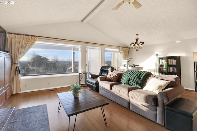 living room with lofted ceiling with beams, a textured ceiling, ceiling fan with notable chandelier, a wealth of natural light, and wood finished floors