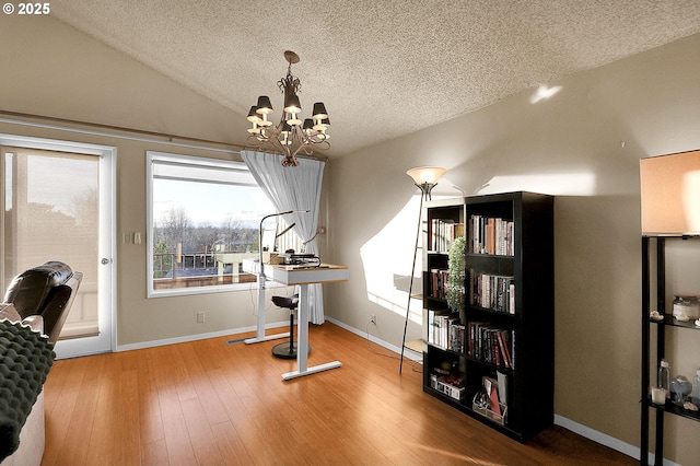 interior space with a textured ceiling, vaulted ceiling, wood finished floors, baseboards, and a chandelier