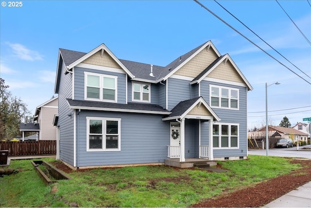 view of front facade featuring a front lawn, fence, and roof with shingles