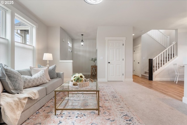 carpeted living room with stairway, baseboards, and wood finished floors