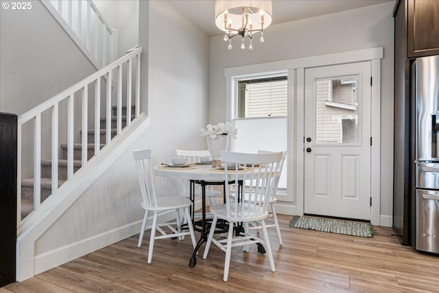 dining room with an inviting chandelier, stairway, baseboards, and light wood-type flooring