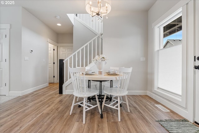dining room featuring visible vents, baseboards, stairway, light wood-type flooring, and a notable chandelier