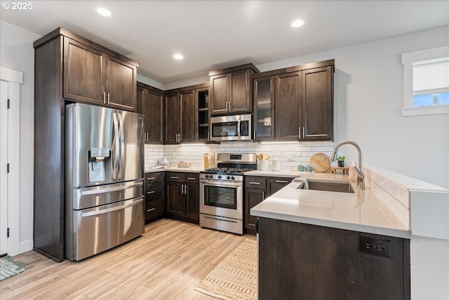 kitchen featuring a sink, stainless steel appliances, backsplash, and dark brown cabinets