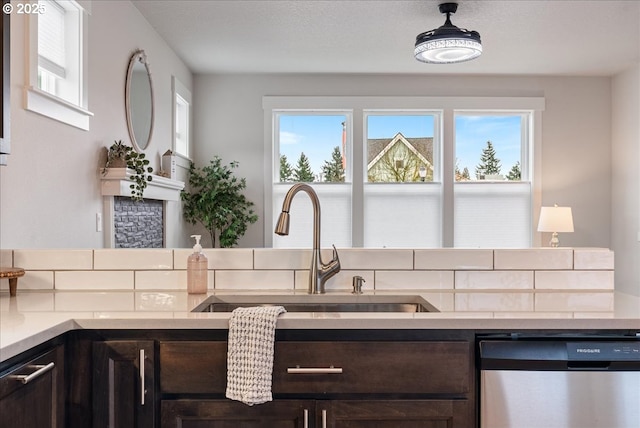 kitchen featuring a sink, dark brown cabinets, plenty of natural light, and stainless steel dishwasher
