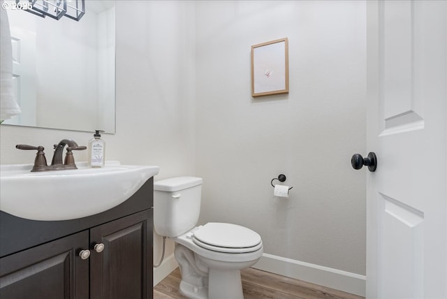 bathroom featuring vanity, toilet, wood finished floors, and baseboards