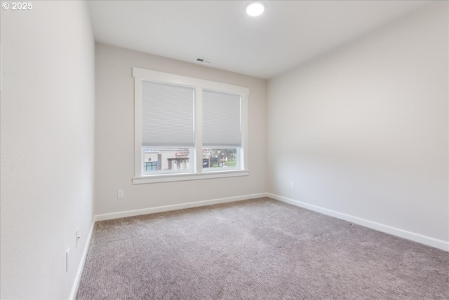 carpeted spare room featuring visible vents and baseboards
