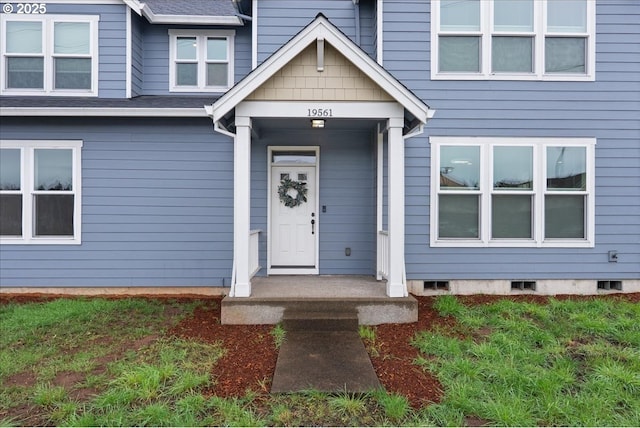 view of exterior entry with roof with shingles and crawl space