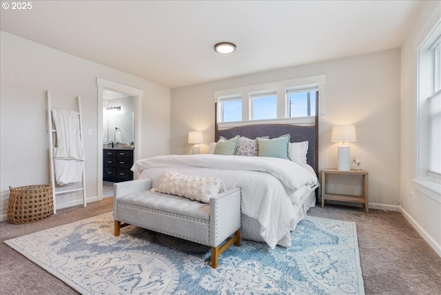 carpeted bedroom featuring connected bathroom and baseboards