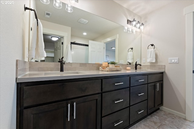 bathroom with double vanity, visible vents, baseboards, and a sink