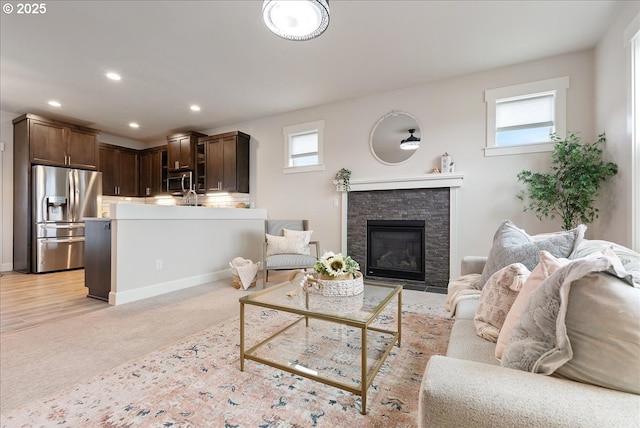 living room featuring a fireplace, recessed lighting, light colored carpet, and a wealth of natural light