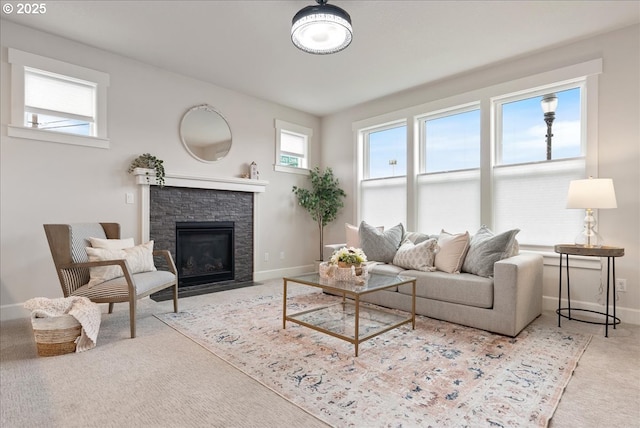 carpeted living room featuring a stone fireplace and baseboards