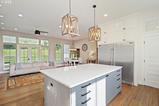 19428 NE 259th St, Battle Ground, WA 98604 - kitchen with stainless steel built in fridge, light wood finished floors, white cabinets, decorative light fixtures, and a center island