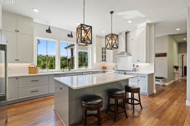 19428 NE 259th St, Battle Ground, WA 98604 - kitchen with wall chimney range hood, backsplash, light wood-style flooring, a center island, and light countertops