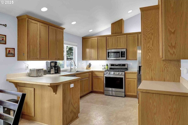 5986 Rombauer Rd, Eugene, OR 97402 - kitchen featuring appliances with stainless steel finishes, a peninsula, vaulted ceiling, a breakfast bar area, and light countertops