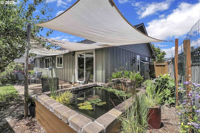 5986 Rombauer Rd, Eugene, OR 97402 - view of property exterior with board and batten siding, a small pond, and a patio