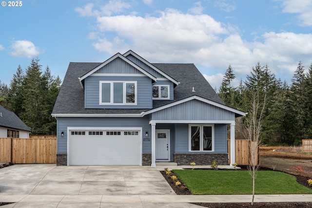 craftsman house featuring stone siding, fence, driveway, and an attached garage