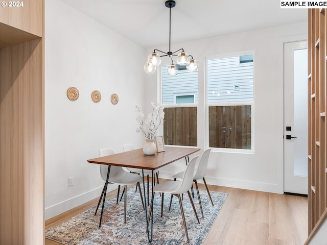 dining room featuring light wood-type flooring, a notable chandelier, and baseboards