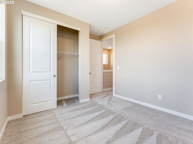 unfurnished bedroom featuring carpet, a closet, and baseboards