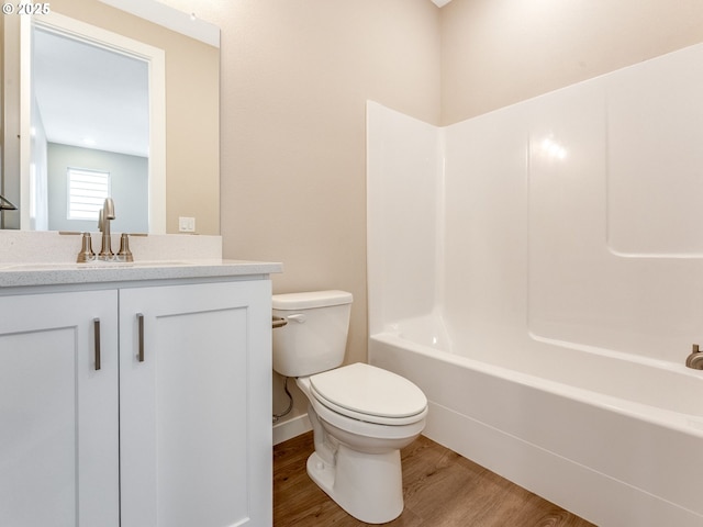 bathroom featuring toilet, wood finished floors, vanity, washtub / shower combination, and baseboards