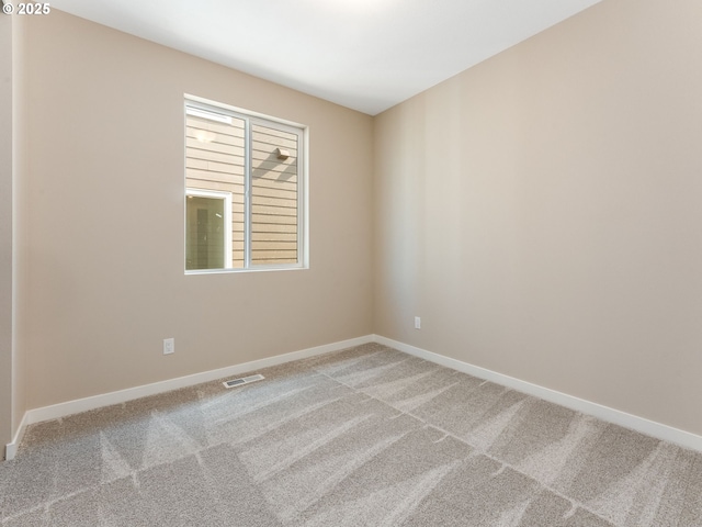 empty room featuring light carpet and baseboards