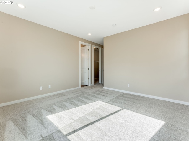 empty room featuring light colored carpet, recessed lighting, and baseboards