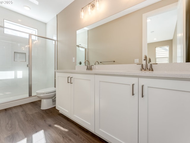 full bathroom with a shower stall, toilet, double vanity, and wood finished floors
